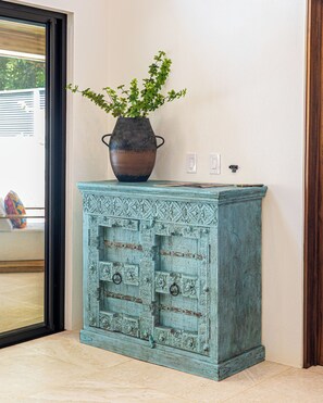 A teal cabinet with intricate carvings and a vase with green foliage on top. - Luxury 3-Bedroom Villa with Private Pool, 100m from Playa Matapalo (Savegre)