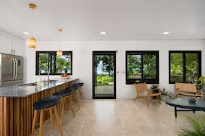 Une cuisine moderne avec un coin bar, de grandes fenêtres et une vue sur la verdure.