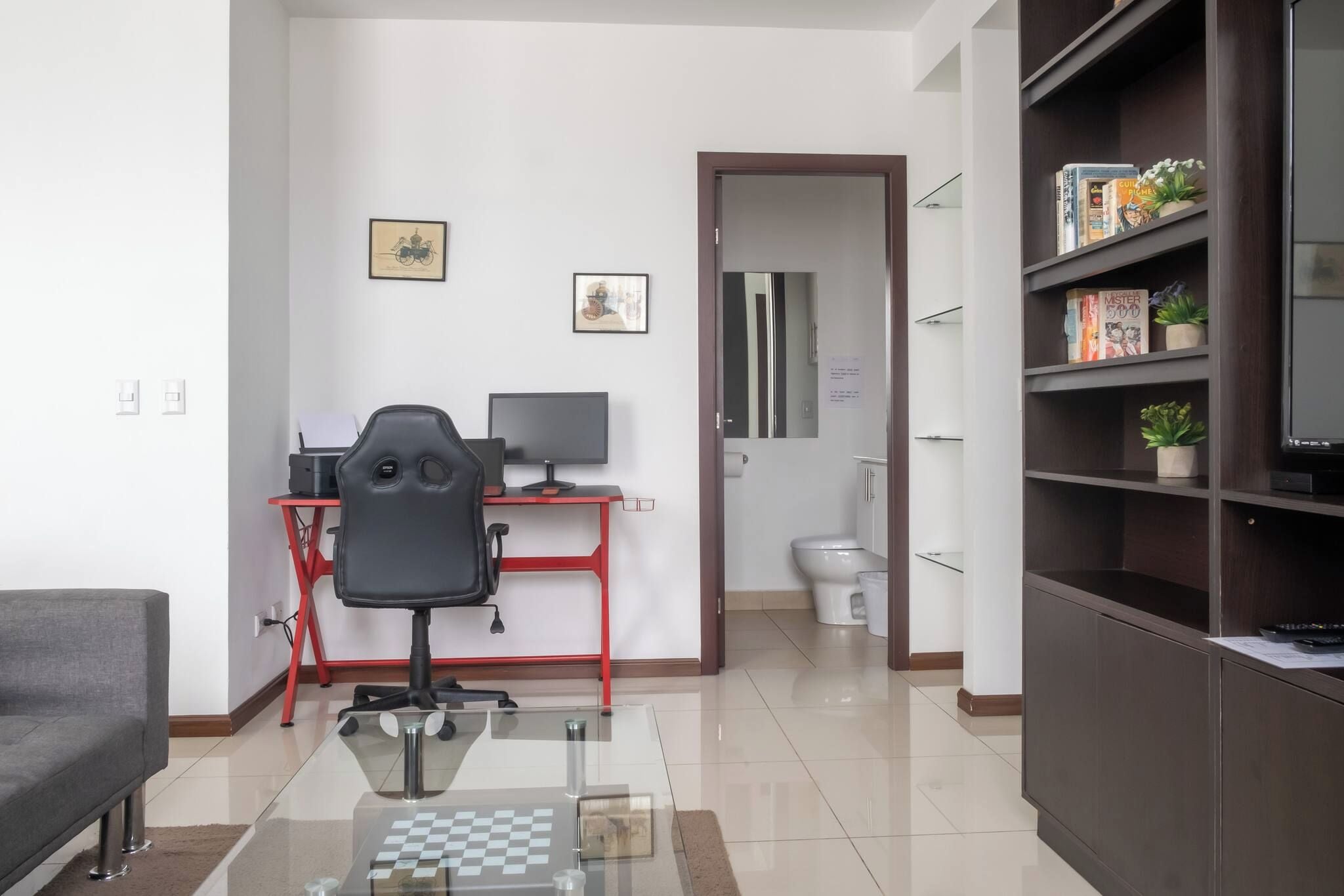 A modern living room with a desk, office chair, and a bookshelf.