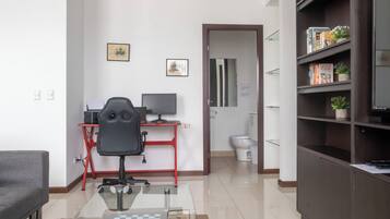A modern living room with a desk, office chair, and a bookshelf.