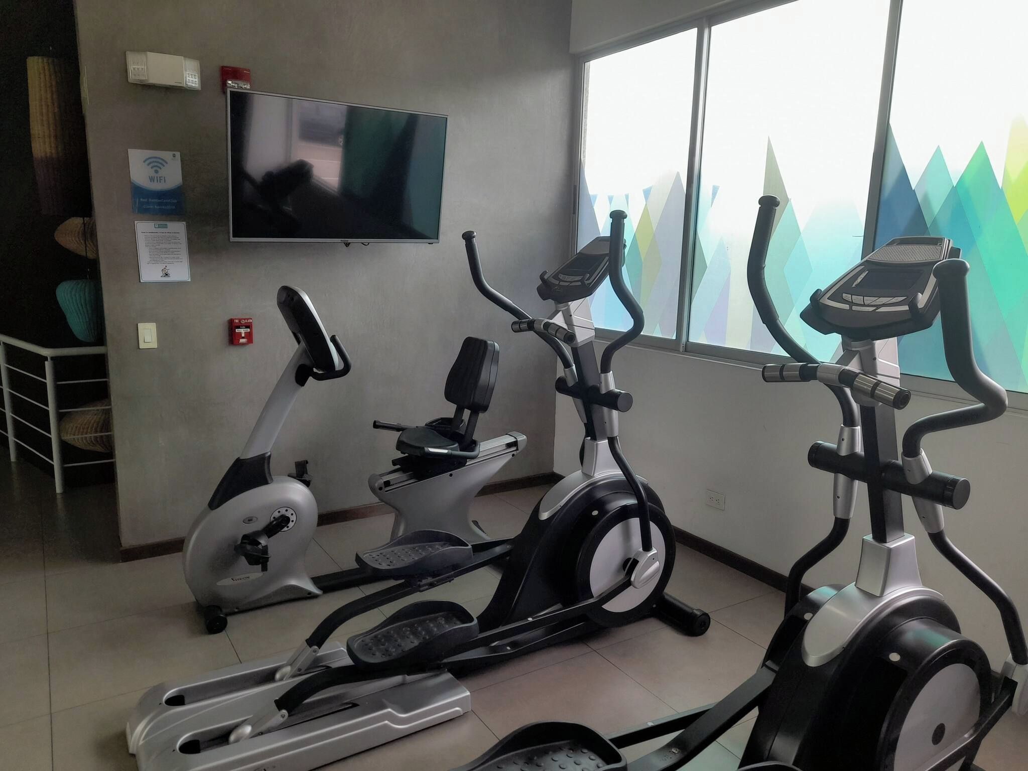 A gym with stationary bikes, a treadmill, and a rowing machine.