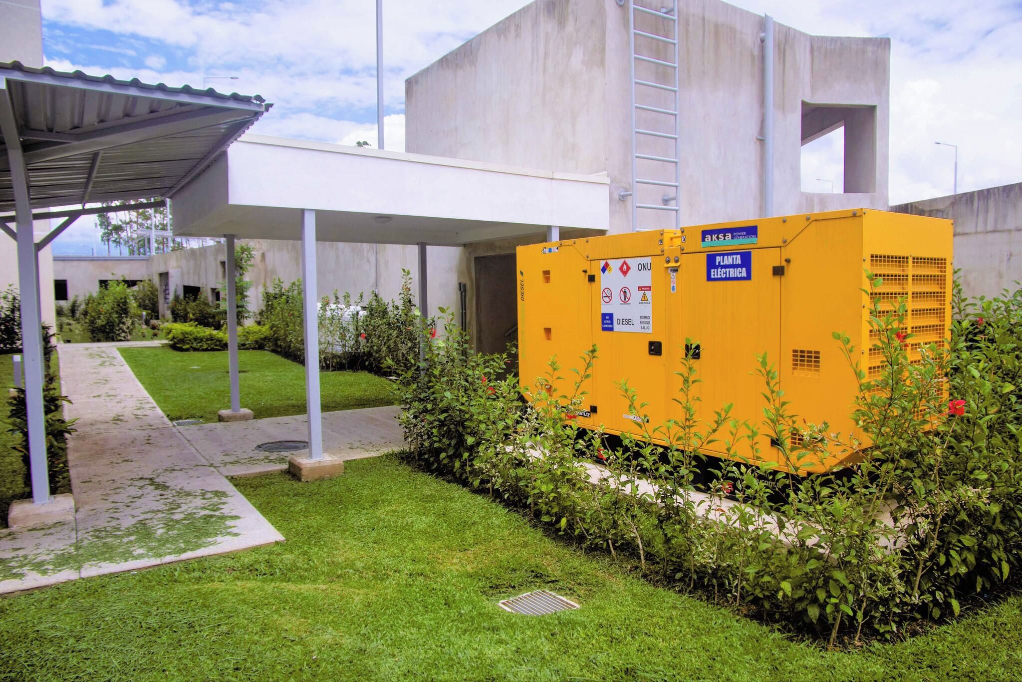 Un cuadro eléctrico amarillo con la etiqueta 'PLANTA ELÉCTRICA', advertencias de seguridad y la etiqueta 'DIESEL'.