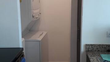 Eine kompakte Küche mit Waschmaschine, kleinem Kühlschrank und Spüle.