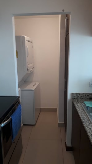 A compact kitchen with a washing machine, a small refrigerator, and a sink.