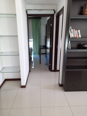 A hallway with a glass door, a bookshelf with books, and a television on a stand.
