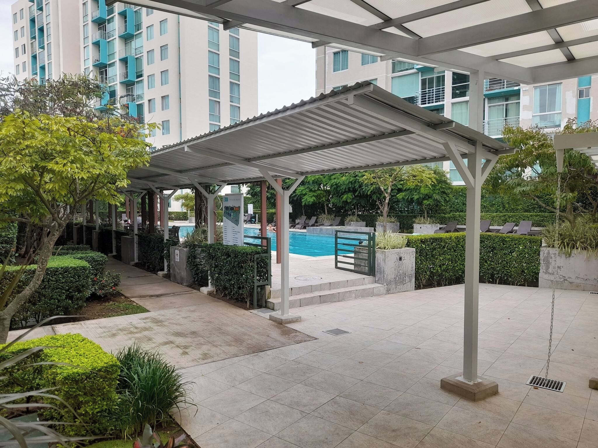 Un espacio al aire libre techado con piscina, sillas de descanso y vistas a rascacielos.