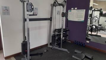 A gym with weightlifting equipment, a bench, and a mirror on the wall.