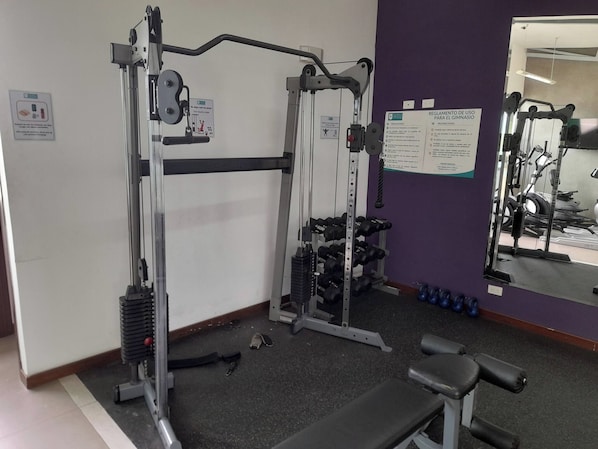 A gym with weightlifting equipment, a bench, and a mirror on the wall. - Condo Washer Dryer Free Indoor Park San José (San José)