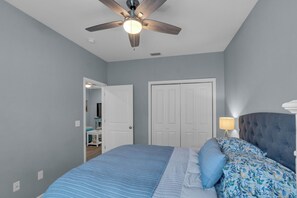 A bedroom with a bed, a ceiling fan, and a nightstand with a lamp. - Aloha PCB: Walk to the Beach - Modern, Impeccable & Fully Stocked (Panama City)
