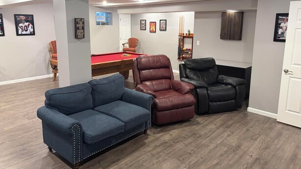Quarto com mesa de bilhar, duas poltronas de couro e um sofá azul.