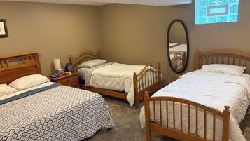 A hotel room with three wooden beds, a large mirror, and a carpeted floor.