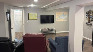 Uma sala de estar com televisão de tela plana, dois sofás, uma mesa de centro e um aparador de vinhos.