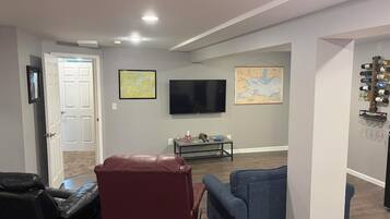 A living room with a flat-screen TV, two sofas, a coffee table, and a wine rack.