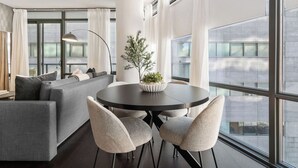 Un salon moderne avec une table ronde, deux chaises, un canapé et une plante en pot.