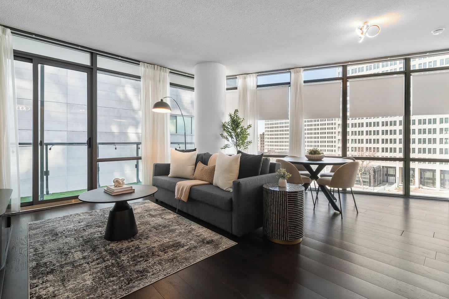 A modern living room with a sofa, coffee table, and a dining area with chairs.