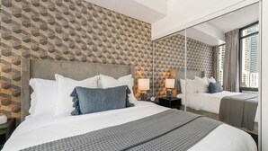 Une chambre d’hôtel avec un grand lit, une table de chevet avec une lampe, un miroir et un mur décoré d’un motif.