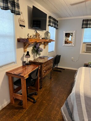 A bedroom with a bed, a desk with a chair, a television, and a window with blinds. - Sunset Cabin (Marshall)