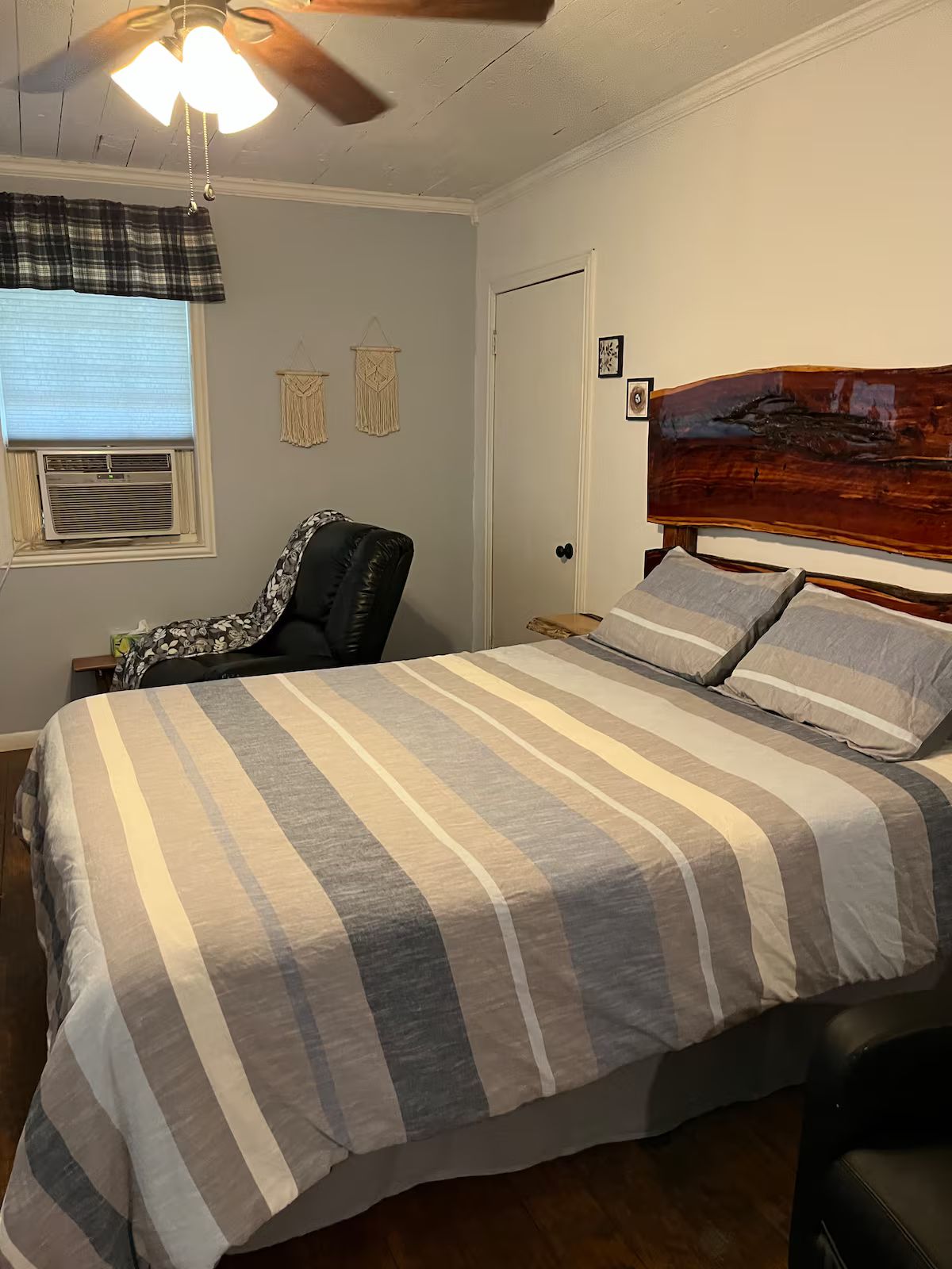 Une chambre à coucher comprenant un lit, une chaise, un ventilateur de plafond et un climatiseur fixé au mur.