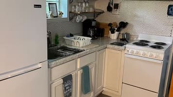 Een keuken met een koelkast, fornuis, magnetron en diverse keukengerei.