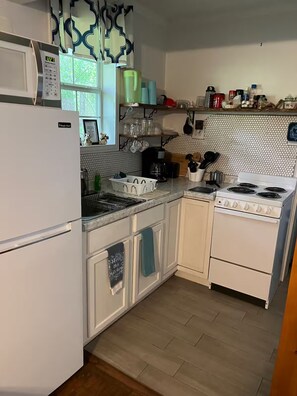 Una cocina equipada con refrigerador, estufa, microondas y diversos utensilios.