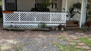 A single-story house with a porch, a small deck, and a gravel driveway.