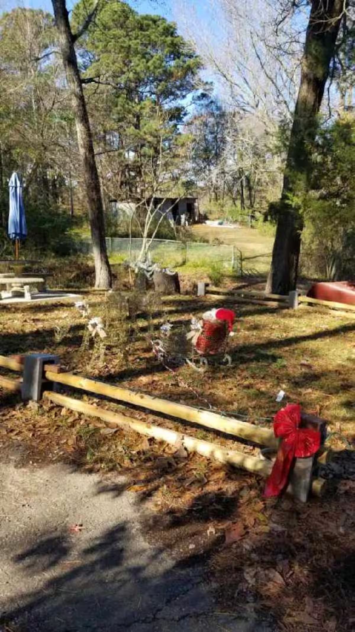 Un parque con un banco de madera, un hidrante rojo y un área cercada.