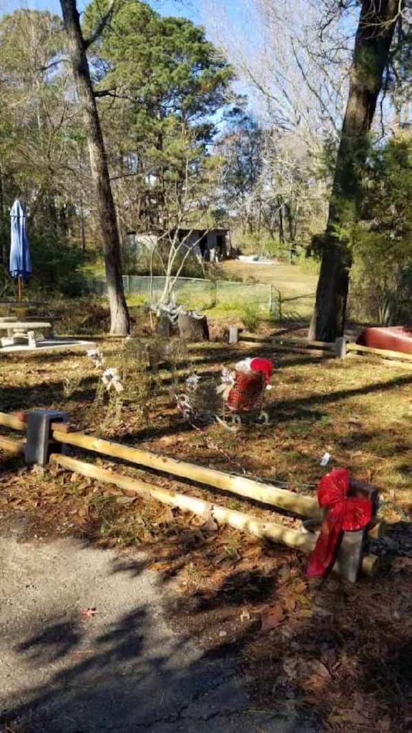 A park with a wooden bench, a red fire hydrant, and a fenced area.