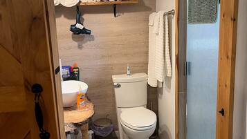 A compact bathroom with a toilet, sink, and shower area.