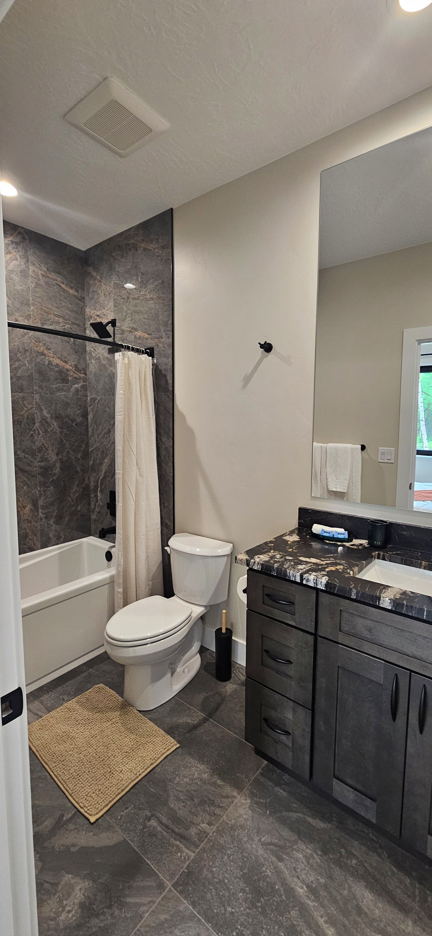 Une salle de bain avec une baignoire, des toilettes et un meuble-lavabo avec un miroir.