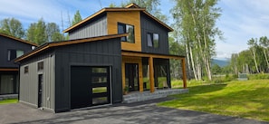 Ein modernes, zweistöckiges Haus mit Garage, großen Fenstern und einer überdachten Veranda.