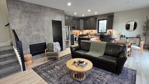Uma sala de estar moderna com lareira, um sofá de couro e um espaço de jantar com mesa e cadeiras.