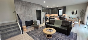 Ein modernes Wohnzimmer mit Kamin, einer Ledersofa und einem Essbereich mit Tisch und Stühlen.