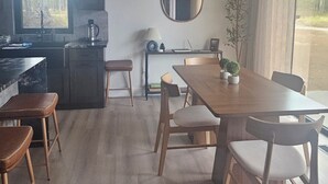 Uma sala de estar moderna com área de jantar, cozinha e uma janela grande.