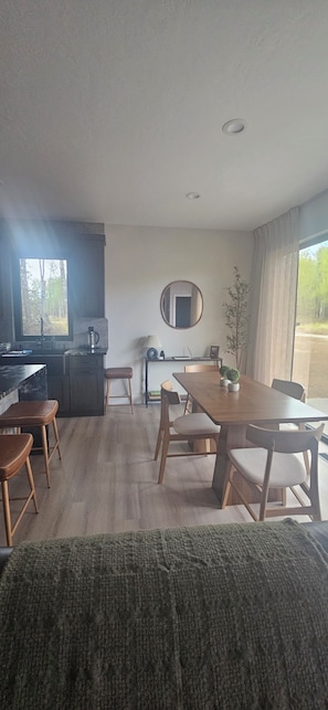 Ein modernes Wohnzimmer mit Essbereich, einer Küche und einem großen Fenster.