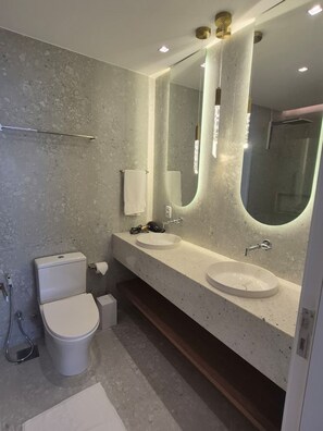 Une salle de bain moderne avec deux lavabos, des toilettes et un grand miroir.