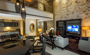 Een moderne hotellobby met een eetgedeelte, zitplaatsen, een televisie en een decoratieve wand.