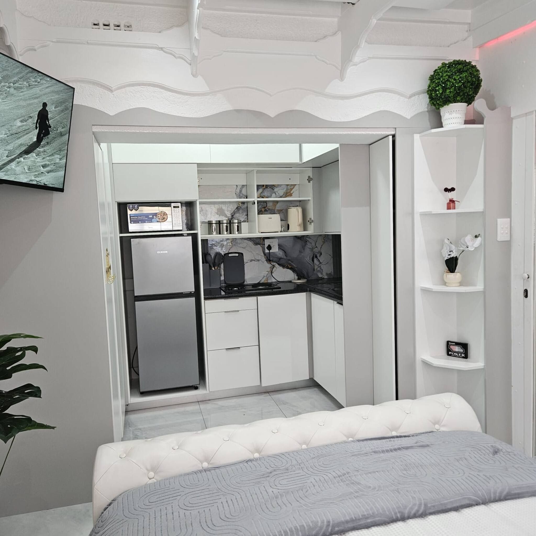 A compact living space with a kitchenette, a bed, and a small seating area.