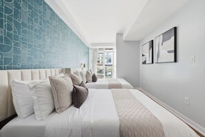 Een hotelkamer met twee bedden, een groot raam en uitzicht op de stad.