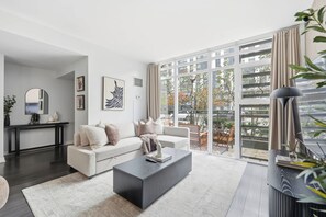 A modern living room with a sofa, coffee table, and artwork on the walls. - 3BR/3BA Downtown Toronto + Free Parking | Parking Available (Toronto)