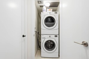 A laundry room with two stacked washing machines and a water heater. - Free Parking! Sleek 2BR steps from CN Tower | Parking Available (Toronto)