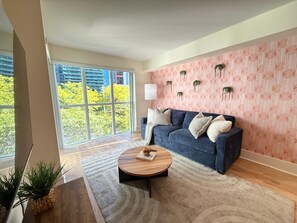 Uma sala de estar moderna com uma janela grande, um sofá azul e uma parede estampada.