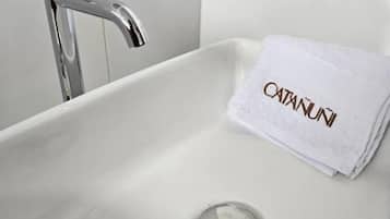 Un baño con un lavabo blanco, un grifo cromado y una toalla con el texto 'CATANUI'.