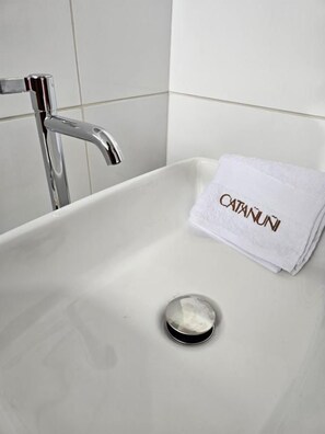 A bathroom with a white sink, a chrome faucet, and a towel with 'CATANUI' text. - Hotel Catañuñi  (Sapallanga)