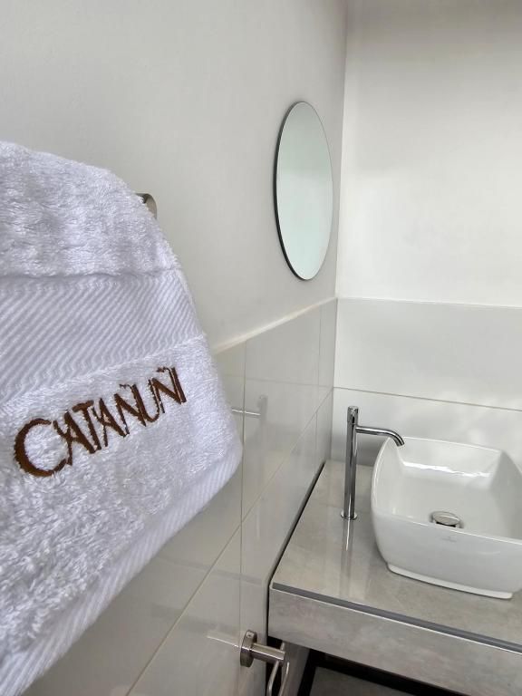 A bathroom with a white towel hanging on a rack, a white sink, and a mirror.