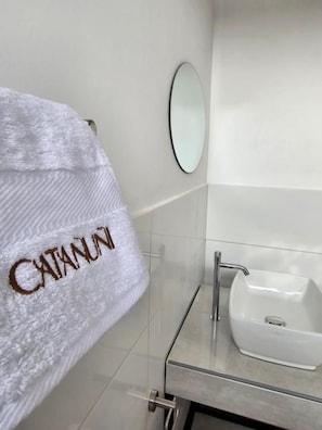 A bathroom with a white towel hanging on a rack, a white sink, and a mirror.