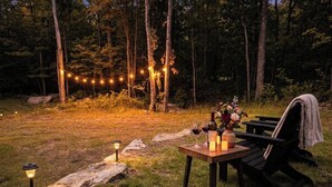 Un área de comedor al aire libre con una mesa dispuesta para dos personas, rodeada por un bosque.