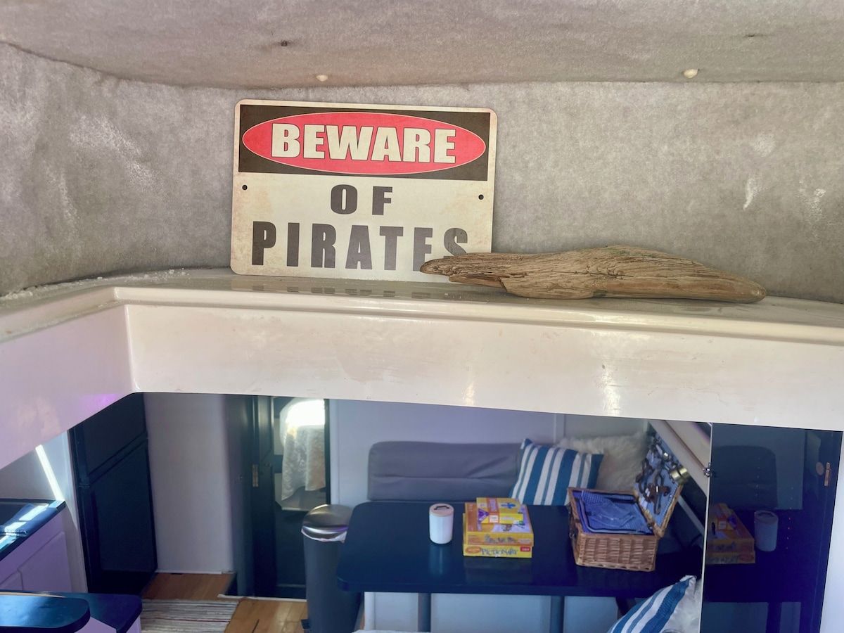A room with a bed, a small table, and a sign warning of pirates.