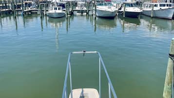 A marina with boats docked at wooden piers, calm water, and a clear sky.