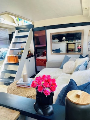 Un dormitorio moderno con una cama, una mesita de noche con un jarrón de flores, una estantería y una escalera.