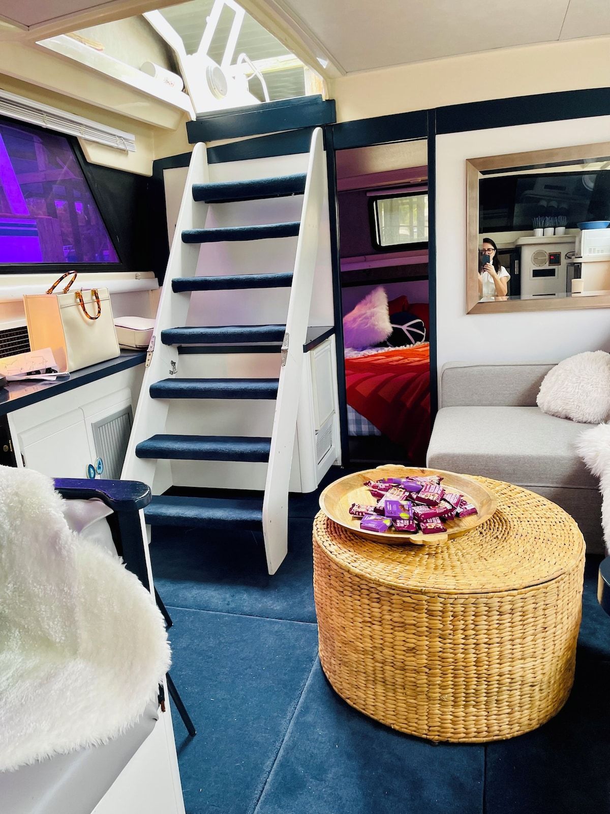 A compact living space with a bunk bed, a desk with a computer, a woven basket with snacks, and a sofa.